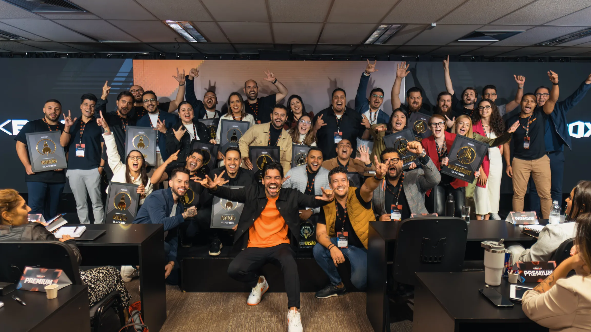 Turma inteira comemorando no palco com as placas de reconhecimento